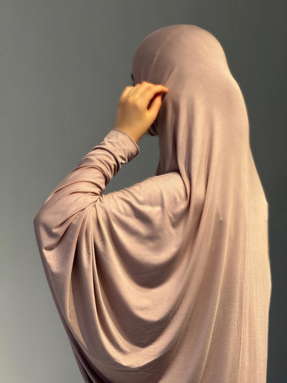 Frau im Jilbab Beige Sahra wendet den Kopf leicht zur Seite, die Rückseite des Outfits zeigt sich weich fließend.